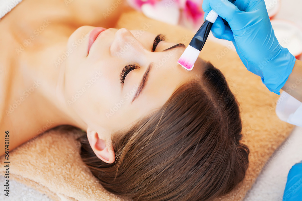Fototapeta premium The woman applies a spa mask to moisturize and care for the skin in beauty studio