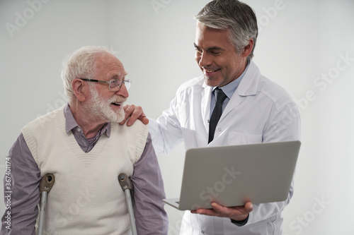 Smiling physician using notebook for aged patient consultation