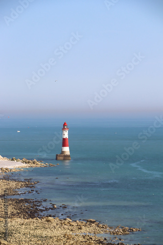 white and red lighthouse in the oceans and blue sky
