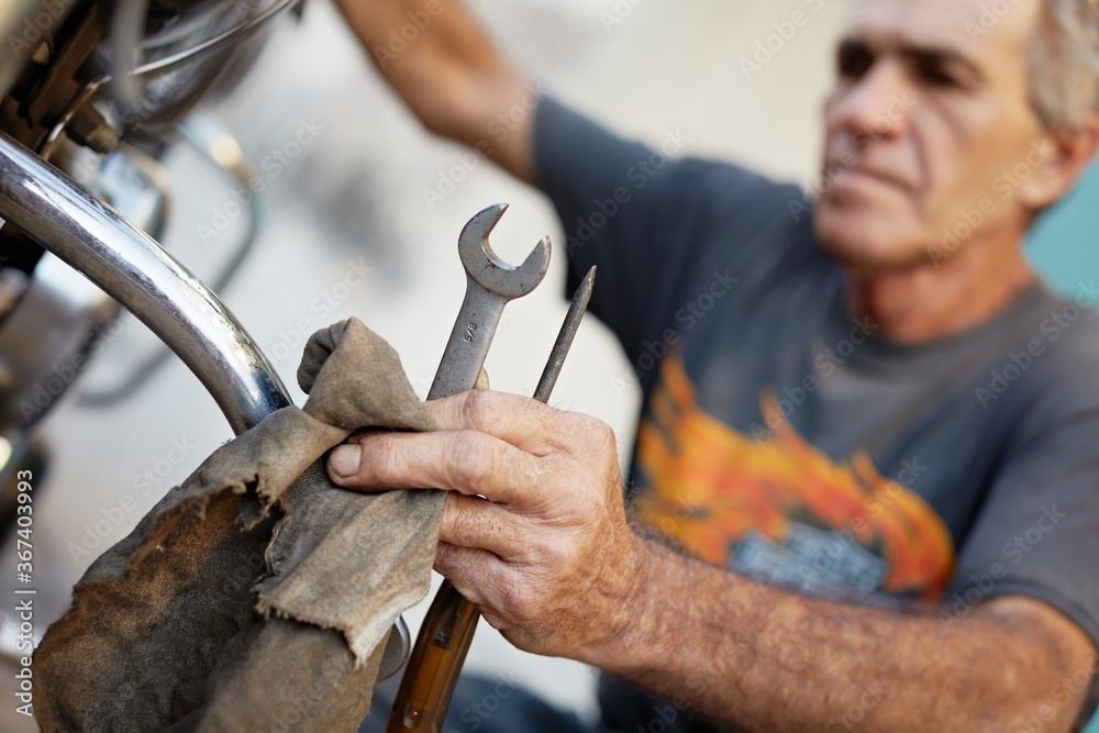 Senior Man Examining His Motorcycle And Fixing Engine