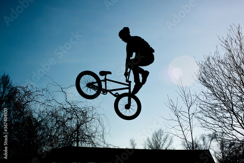 View from below strong athlete jumping in air. Guy performs tricks on a bike. Concept of adrenaline.