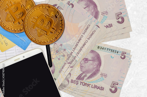 5 Turkish lira bills and golden bitcoins with smartphone and credit cards. Cryptocurrency investment concept. Crypto mining or trading photo