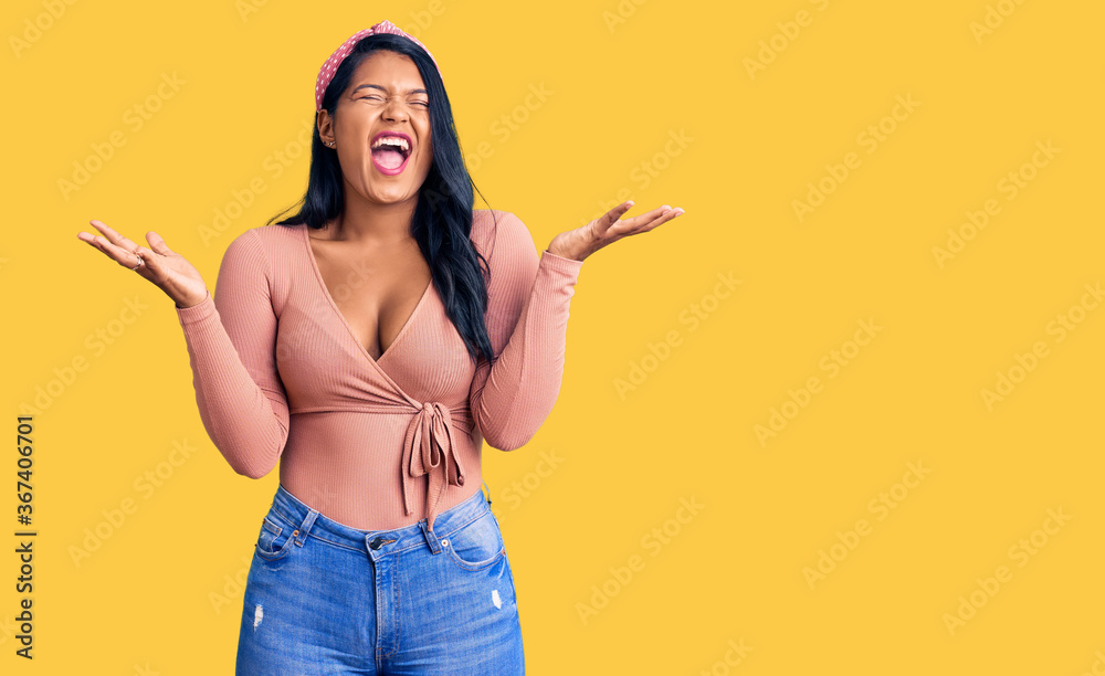 Hispanic woman with long hair wearing casual clothes celebrating mad and crazy for success with arms raised and closed eyes screaming excited. winner concept Hispanic woman with long hair wearing casual clothes celebrating mad and crazy for success with arms raised and closed eyes screaming excited. winner concept