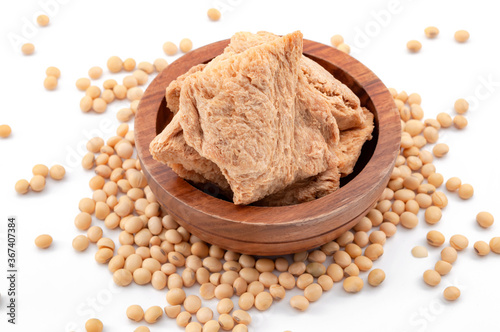 Vegetarian alternative to meat and vegan food option concept with photograph of soya textured chunks in wooden bowl and soy beans isolated on white background