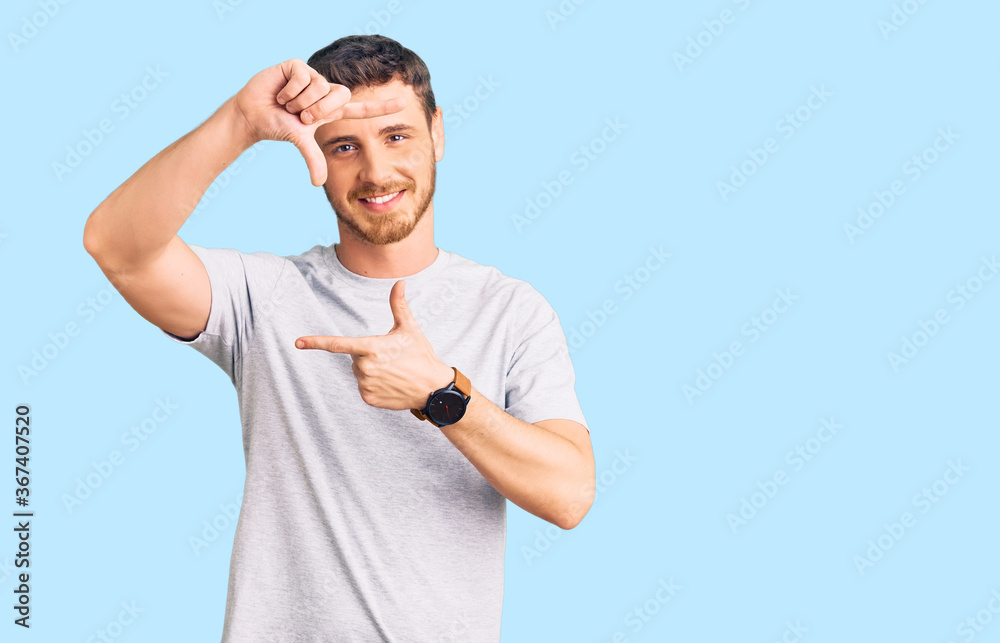 Handsome young man with bear wearing casual tshirt smiling making frame with hands and fingers with happy face. creativity and photography concept. Handsome young man with bear wearing casual tshirt smiling making frame with hands and fingers with happy face. creativity and photography concept.