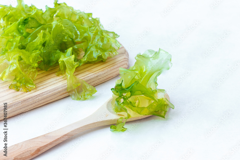 fresh green seaweed leaves, for making salad, on a wooden Board, light background, horizontally fresh green seaweed leaves, for making salad, on a wooden Board, light background, horizontally