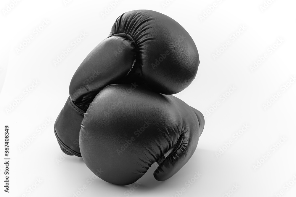 Competitive sports, fist protection and martial arts concept with photograph of two black boxing gloves with one glove on top of the other isolated on white background with clipping path cutout