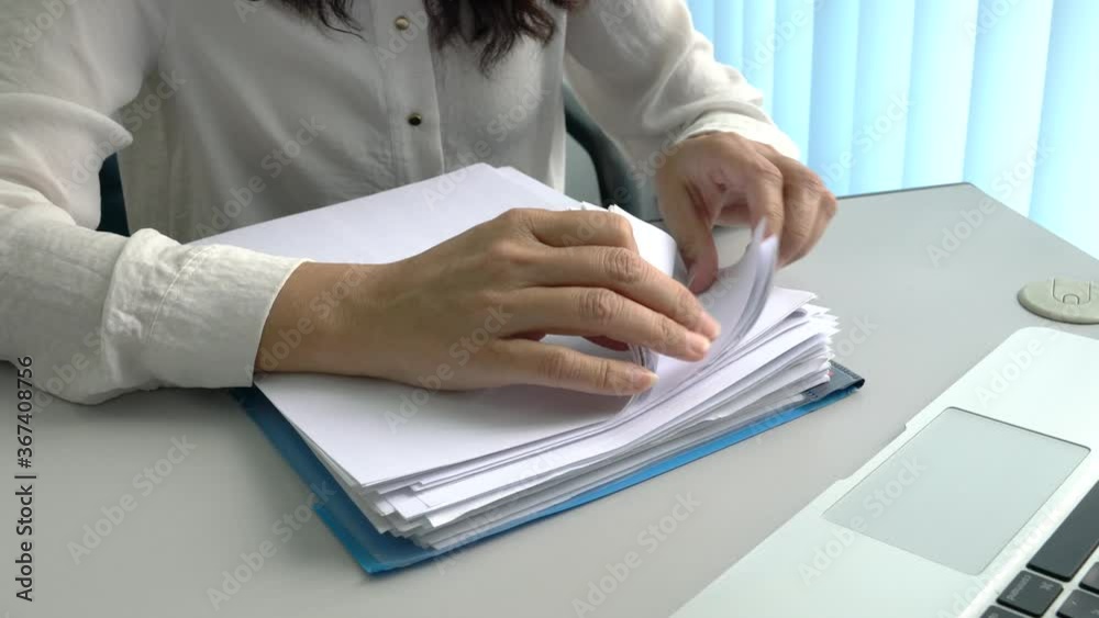 Businesswoman searching through a pile of documents on top of table