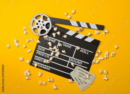 фотографія Single, black, open movie clapper or clapper-board with film reel, popcorn and m
