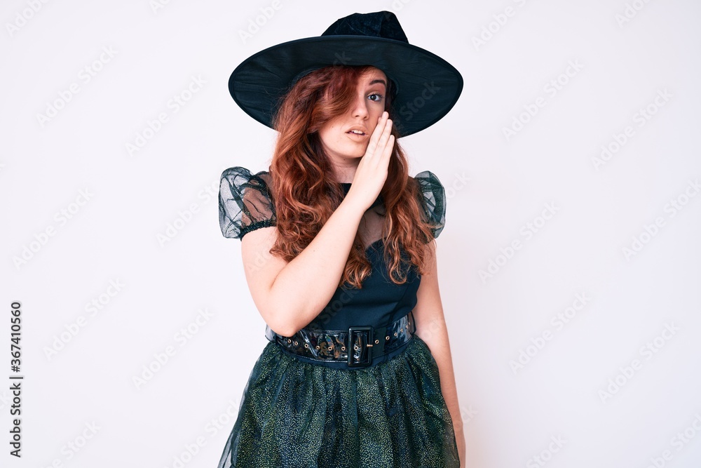 Young beautiful woman wearing witch halloween costume hand on mouth telling secret rumor, whispering malicious talk conversation Young beautiful woman wearing witch halloween costume hand on mouth telling secret rumor, whispering malicious talk conversation