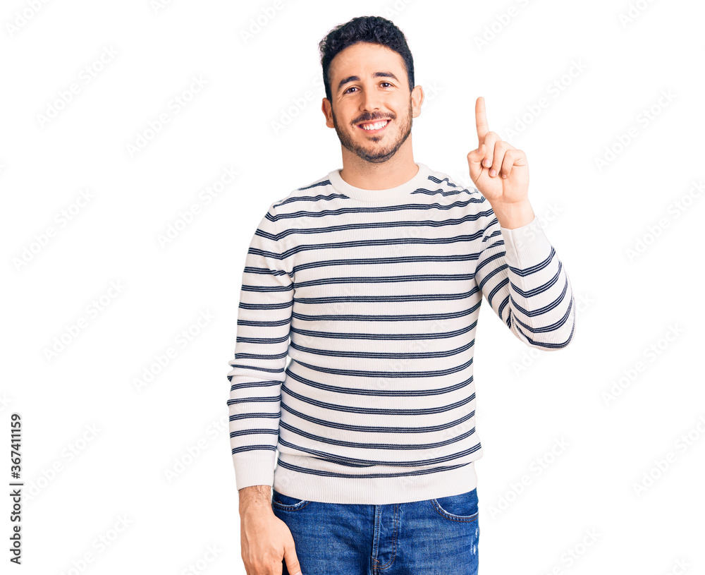 Young hispanic man wearing casual clothes showing and pointing up with finger number one while smiling confident and happy. Young hispanic man wearing casual clothes showing and pointing up with finger number one while smiling confident and happy.