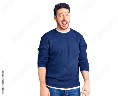 Young hispanic man wearing casual clothes winking looking at the camera with sexy expression, cheerful and happy face.