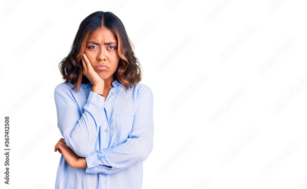 Young beautiful mixed race woman wearing casual business shirt thinking looking tired and bored with depression problems with crossed arms. Young beautiful mixed race woman wearing casual business shirt thinking looking tired and bored with depression problems with crossed arms.