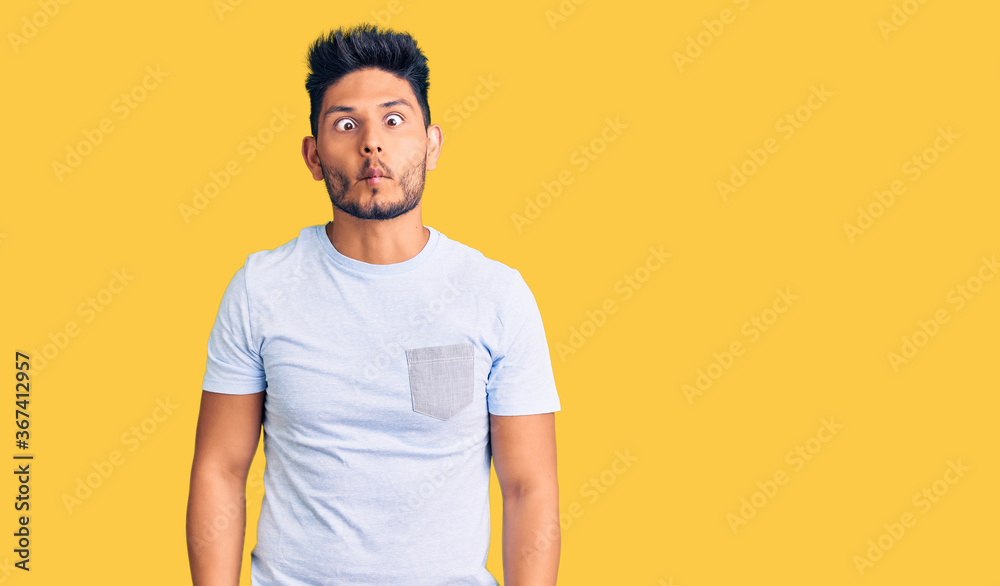 Handsome latin american young man wearing casual clothes making fish face with lips, crazy and comical gesture. funny expression. Handsome latin american young man wearing casual clothes making fish face with lips, crazy and comical gesture. funny expression.