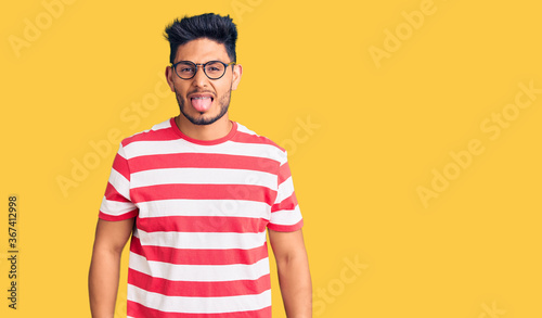 Wallpaper Mural Handsome latin american young man wearing casual clothes and glasses sticking tongue out happy with funny expression. emotion concept. Torontodigital.ca