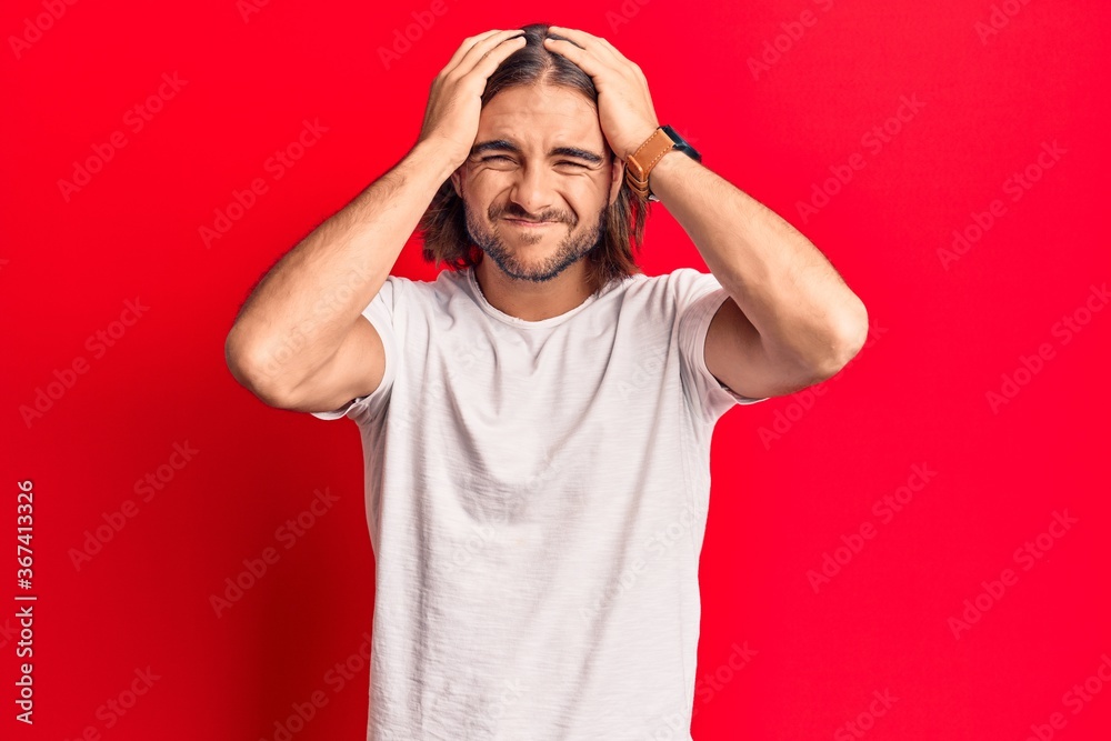 Young handsome man wearing casual clothes suffering from headache desperate and stressed because pain and migraine. hands on head. Young handsome man wearing casual clothes suffering from headache desperate and stressed because pain and migraine. hands on head.