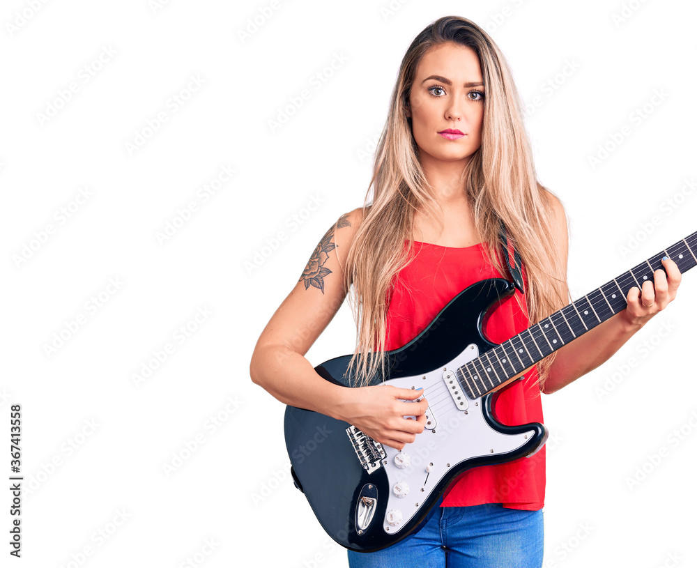 Young beautiful blonde woman playing electric guitar thinking attitude and sober expression looking self confident Young beautiful blonde woman playing electric guitar thinking attitude and sober expression looking self confident