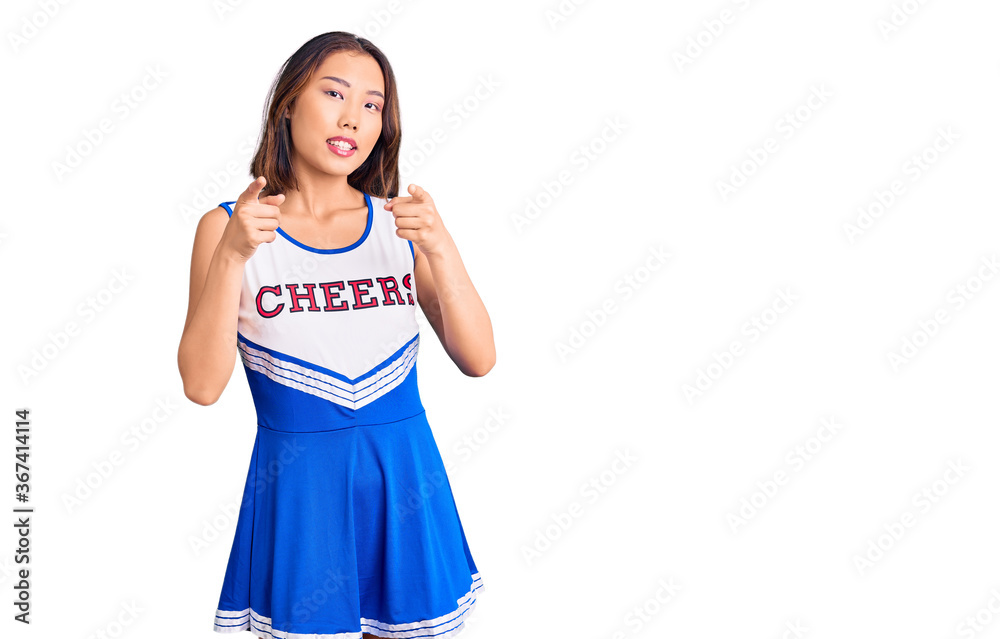 Fototapeta premium Young beautiful chinese girl wearing cheerleader uniform pointing fingers to camera with happy and funny face. good energy and vibes.