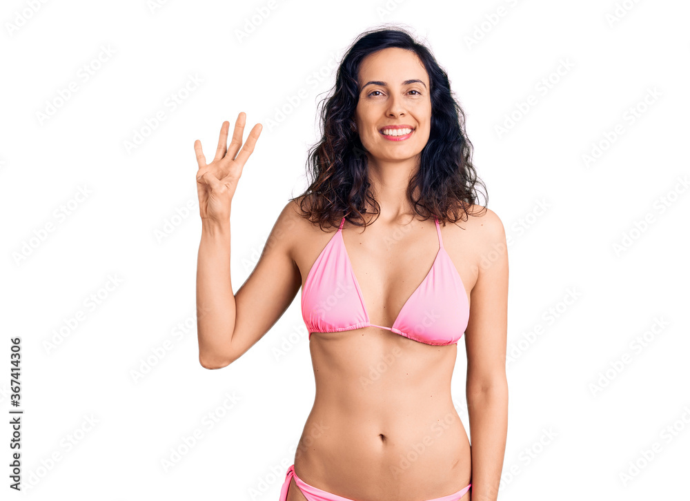Young beautiful hispanic woman wearing bikini showing and pointing up with fingers number four while smiling confident and happy. Young beautiful hispanic woman wearing bikini showing and pointing up with fingers number four while smiling confident and happy.