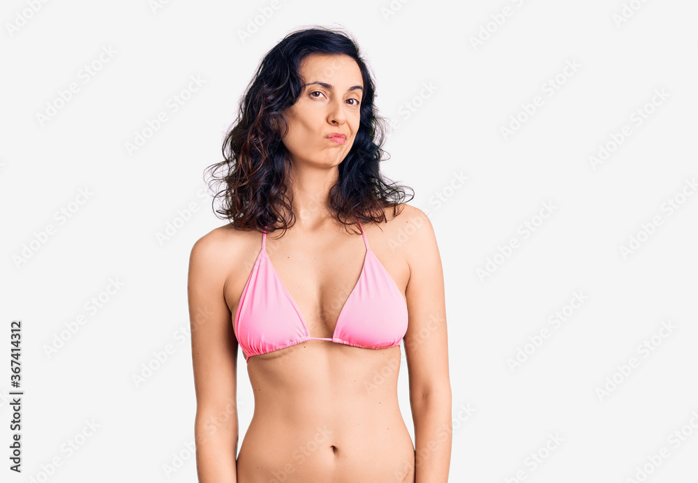 Fototapeta premium Young beautiful hispanic woman wearing bikini looking sleepy and tired, exhausted for fatigue and hangover, lazy eyes in the morning.