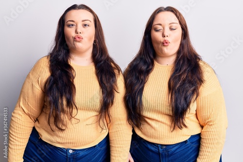 Young plus size twins wearing casual clothes making fish face with lips  crazy and comical gesture. funny expression.