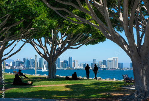 San Diego Skyline Destination City View.  People silhouetted at Spanish Landing Park sightseeing buildings and bay water.