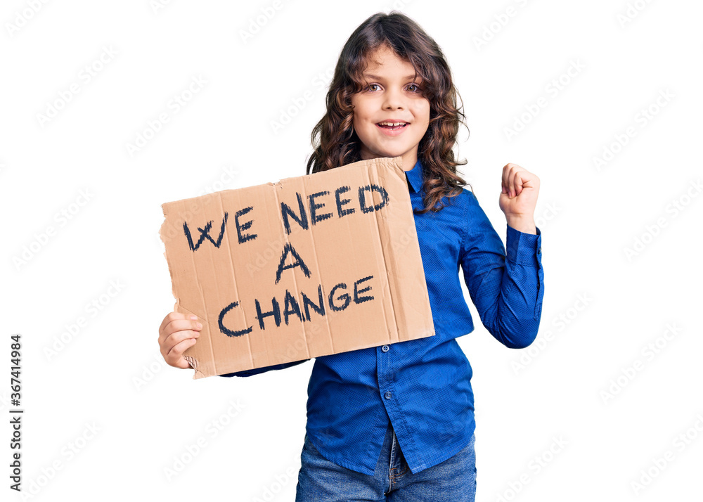 Cute hispanic child with long hair holding we need a change banner screaming proud, celebrating victory and success very excited with raised arms Cute hispanic child with long hair holding we need a change banner screaming proud, celebrating victory and success very excited with raised arms