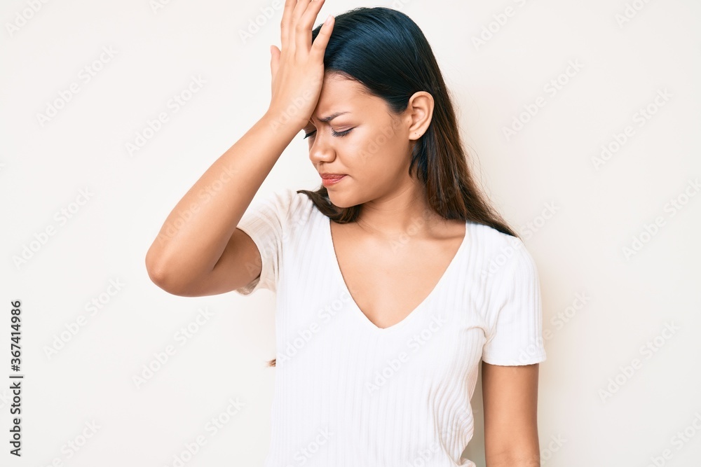 Young beautiful latin girl wearing casual white tshirt surprised with hand on head for mistake, remember error. forgot, bad memory concept. Young beautiful latin girl wearing casual white tshirt surprised with hand on head for mistake, remember error. forgot, bad memory concept.