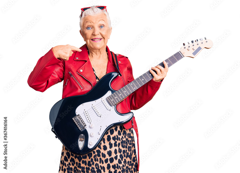 Senior beautiful woman with blue eyes and grey hair wearing a modern look playing electric guitar smiling cheerful showing and pointing with fingers teeth and mouth. dental health concept.