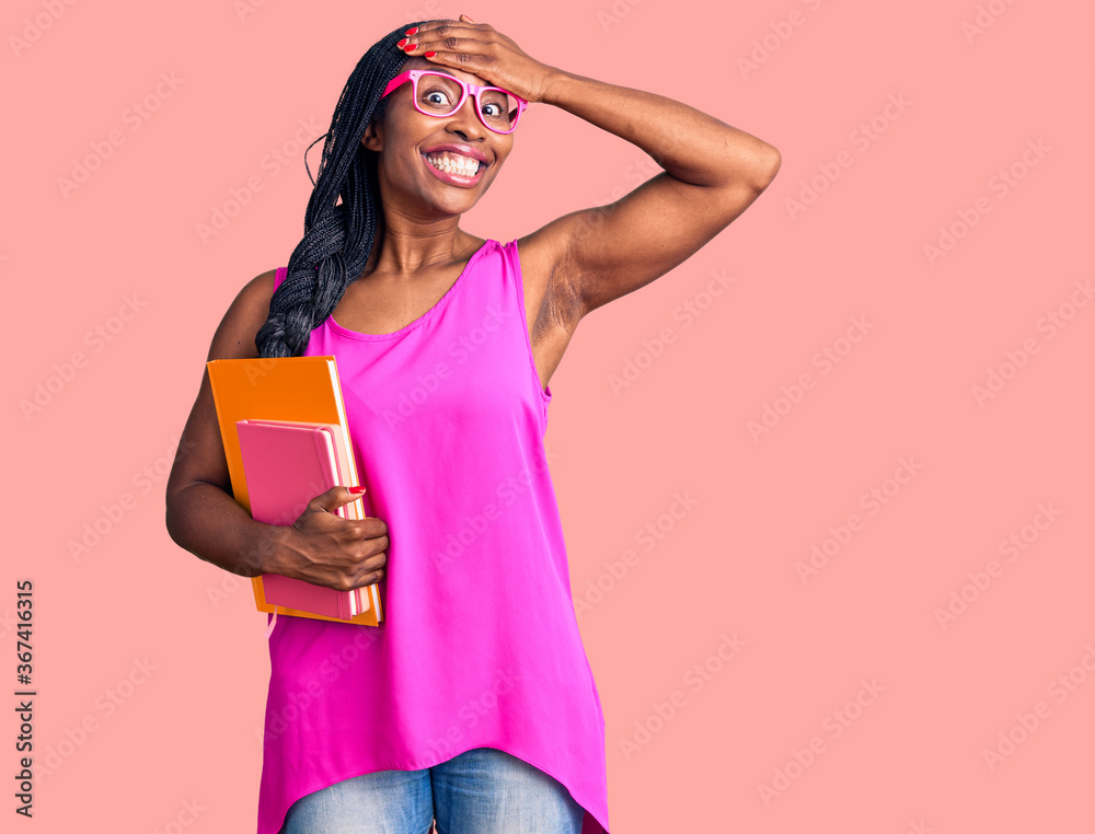 Young african american woman wearing glasses holding book stressed and frustrated with hand on head, surprised and angry face Young african american woman wearing glasses holding book stressed and frustrated with hand on head, surprised and angry face