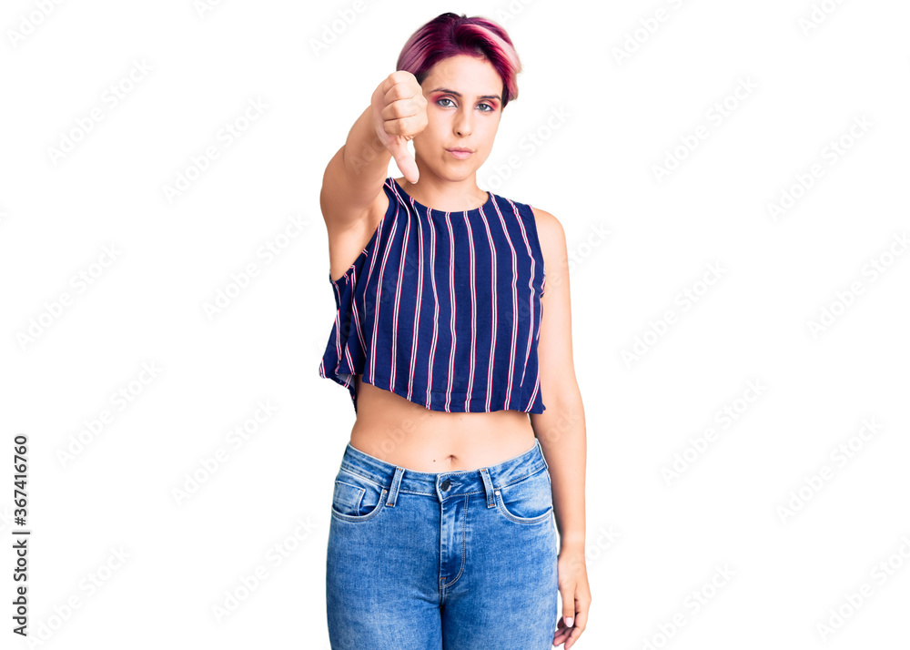 Young beautiful woman with pink hair wearing casual clothes looking unhappy and angry showing rejection and negative with thumbs down gesture. bad expression. Young beautiful woman with pink hair wearing casual clothes looking unhappy and angry showing rejection and negative with thumbs down gesture. bad expression.