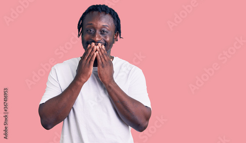 Schilderij op canvas Young african american man with braids wearing casual white tshirt laughing and
