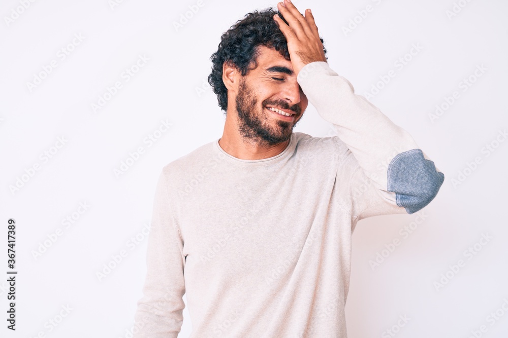 Handsome young man with curly hair and bear wearing casual winter sweater surprised with hand on head for mistake, remember error. forgot, bad memory concept. Handsome young man with curly hair and bear wearing casual winter sweater surprised with hand on head for mistake, remember error. forgot, bad memory concept.