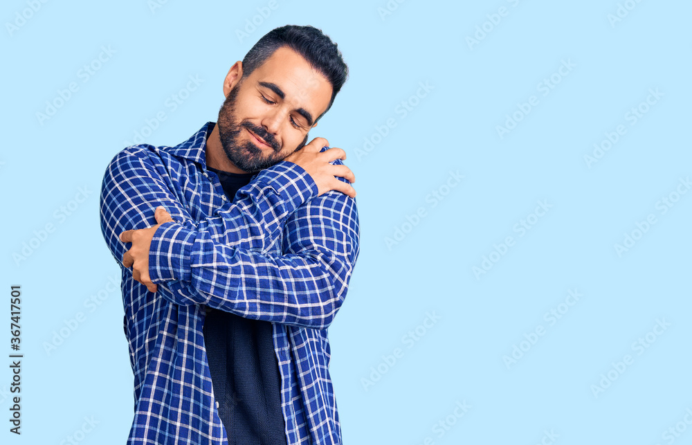 Young hispanic man wearing casual clothes hugging oneself happy and positive, smiling confident. self love and self care Young hispanic man wearing casual clothes hugging oneself happy and positive, smiling confident. self love and self care