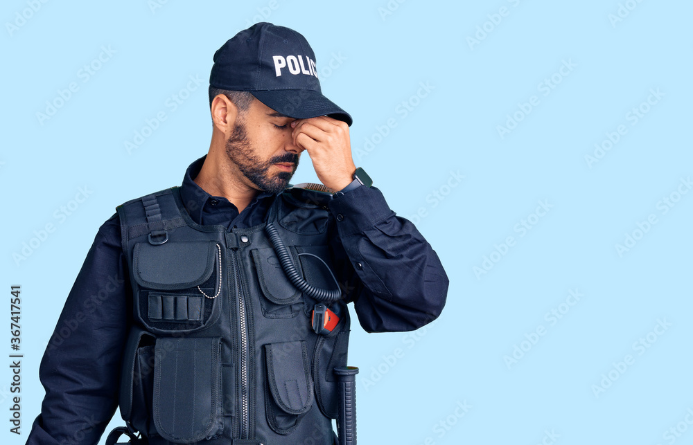 Young hispanic man wearing police uniform tired rubbing nose and eyes feeling fatigue and headache. stress and frustration concept. Young hispanic man wearing police uniform tired rubbing nose and eyes feeling fatigue and headache. stress and frustration concept.