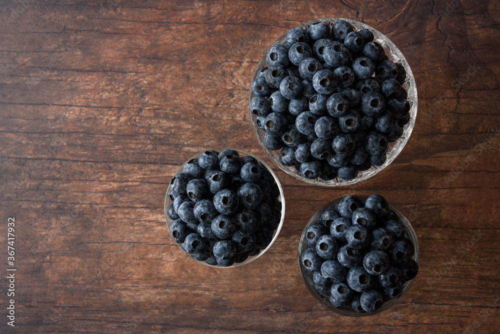 Top view of fresh blueberries in three glass bowls on a rustic wood table
Top view of fresh blueberries in three glass bowls on a rustic wood table