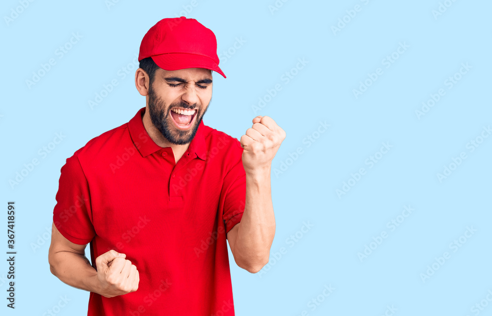 Young handsome man with beard wearing delivery uniform celebrating surprised and amazed for success with arms raised and eyes closed. winner concept.