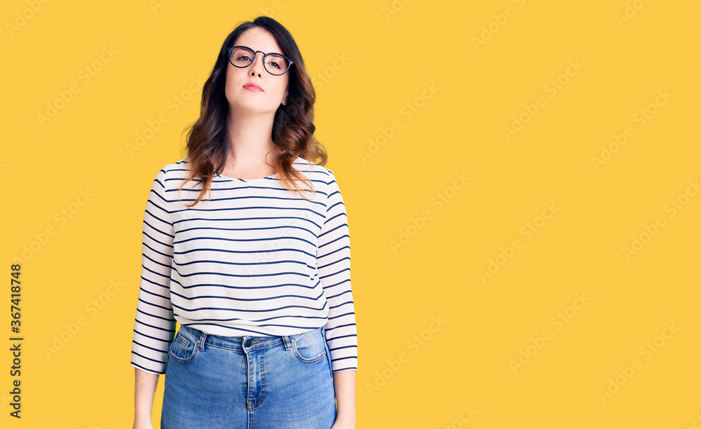 Beautiful young brunette woman wearing casual clothes and glasses relaxed with serious expression on face. simple and natural looking at the camera. Beautiful young brunette woman wearing casual clothes and glasses relaxed with serious expression on face. simple and natural looking at the camera.