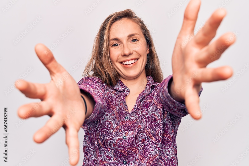 Young beautiful blonde woman wearing boho shirt standing over isolated background looking at the camera smiling with open arms for hug. cheerful expression embracing happiness. Young beautiful blonde woman wearing boho shirt standing over isolated background looking at the camera smiling with open arms for hug. cheerful expression embracing happiness.