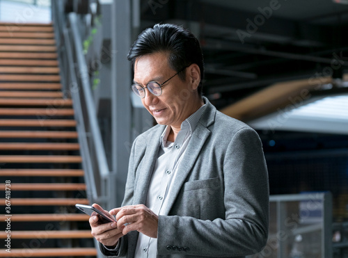 Chinese businessman looking at his cellphone in his hand.