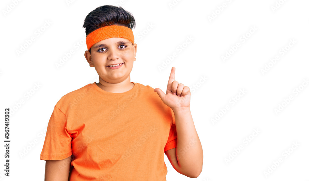 Little boy kid wearing sportswear with a big smile on face, pointing with hand finger to the side looking at the camera. Little boy kid wearing sportswear with a big smile on face, pointing with hand finger to the side looking at the camera.