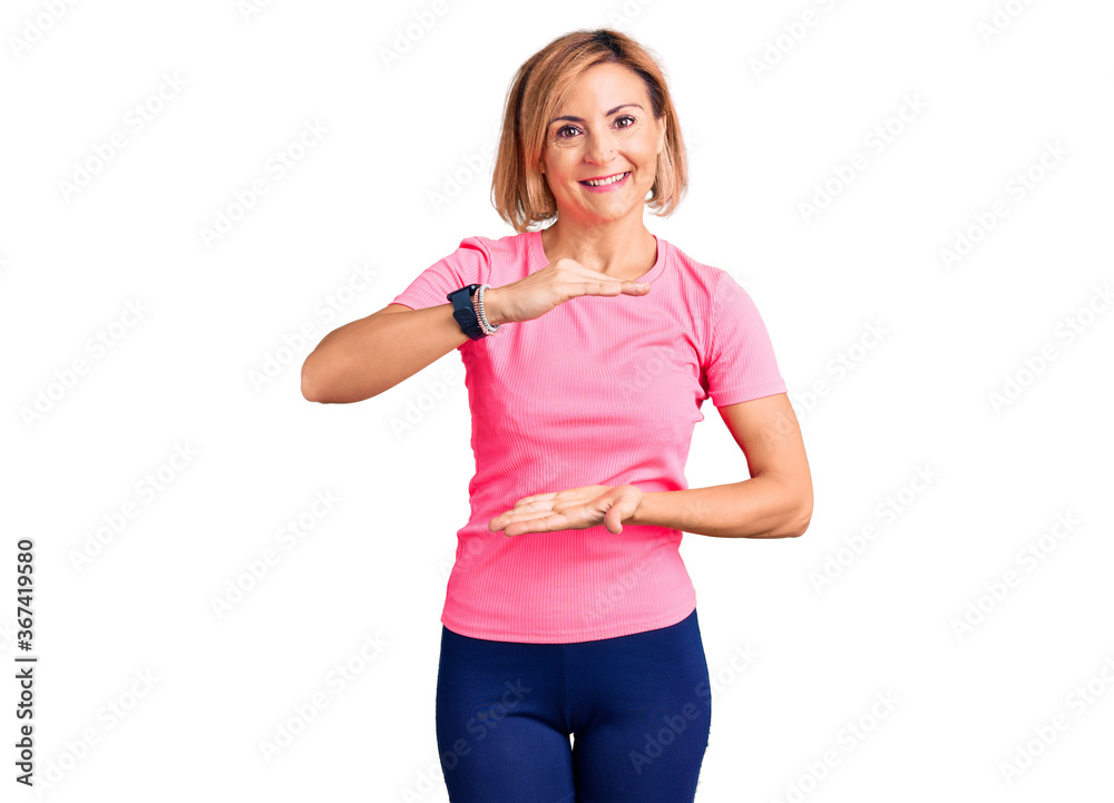 Young blonde woman wearing sportswear gesturing with hands showing big and large size sign, measure symbol. smiling looking at the camera. measuring concept. Young blonde woman wearing sportswear gesturing with hands showing big and large size sign, measure symbol. smiling looking at the camera. measuring concept.