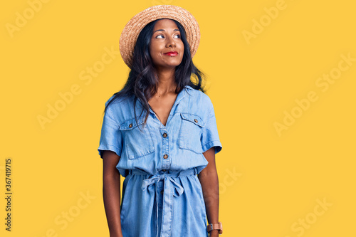 Young indian girl wearing summer hat smiling looking to the side and staring away thinking. © Krakenimages.com