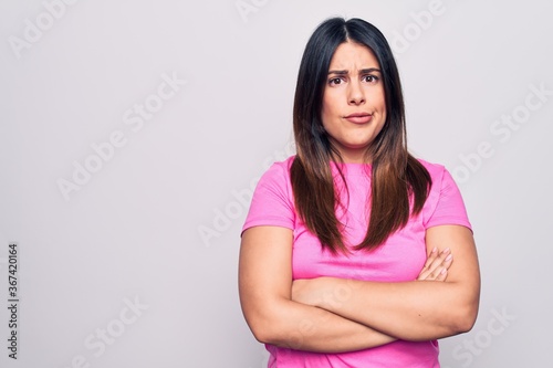 Young beautiful brunette woman wearing casual pink t-shirt standing over white background skeptic and nervous, disapproving expression on face with crossed arms. Negative person.