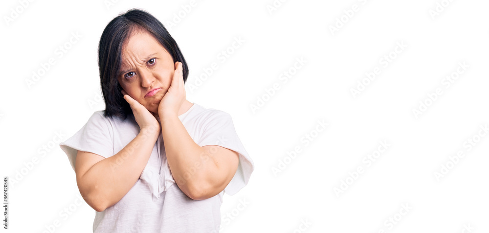 Brunette woman with down syndrome wearing casual white tshirt tired hands covering face, depression and sadness, upset and irritated for problem Brunette woman with down syndrome wearing casual white tshirt tired hands covering face, depression and sadness, upset and irritated for problem