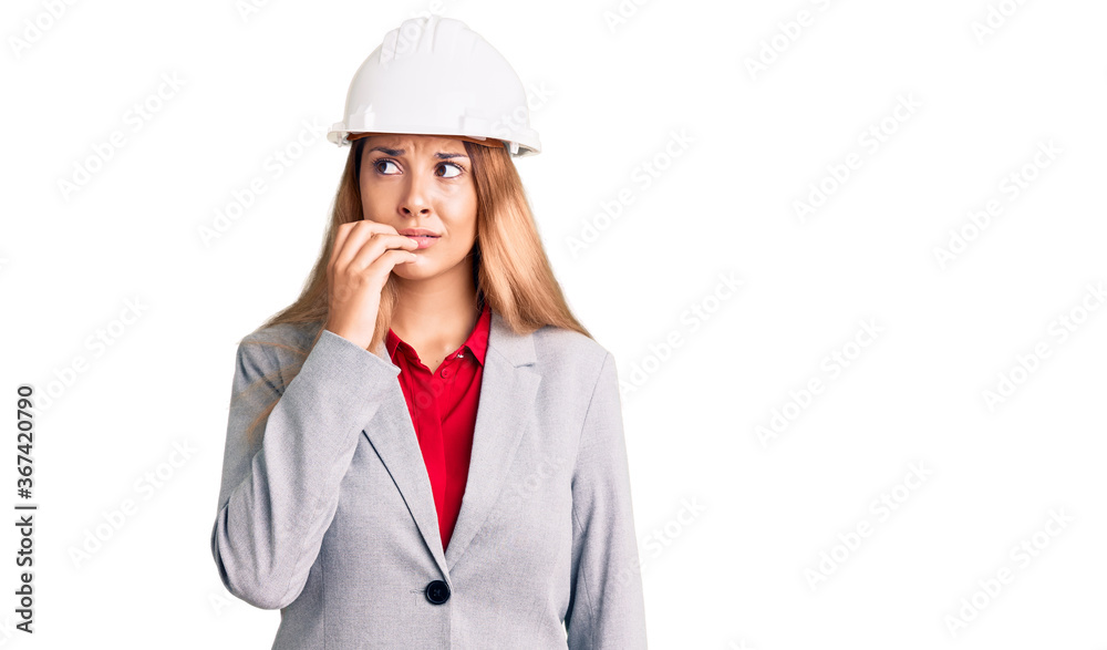 Beautiful young woman wearing architect hardhat looking stressed and nervous with hands on mouth biting nails. anxiety problem.