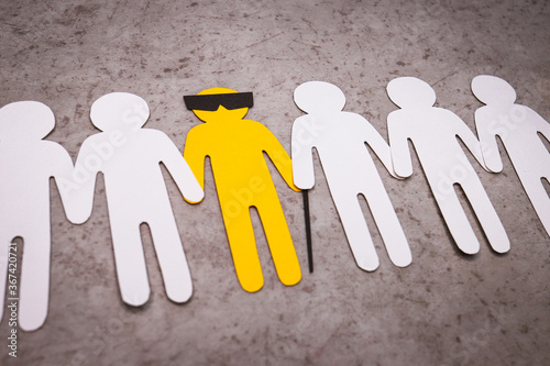 The silhouette of a blind man with a cane and glasses. People stand in a line and support the yellow figure by the hands. A disabled person is a full-fledged part of society.