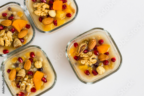 Traditional Turkish Dessert Ashura or Noah's Pudding in glass bowls on white with copy space.