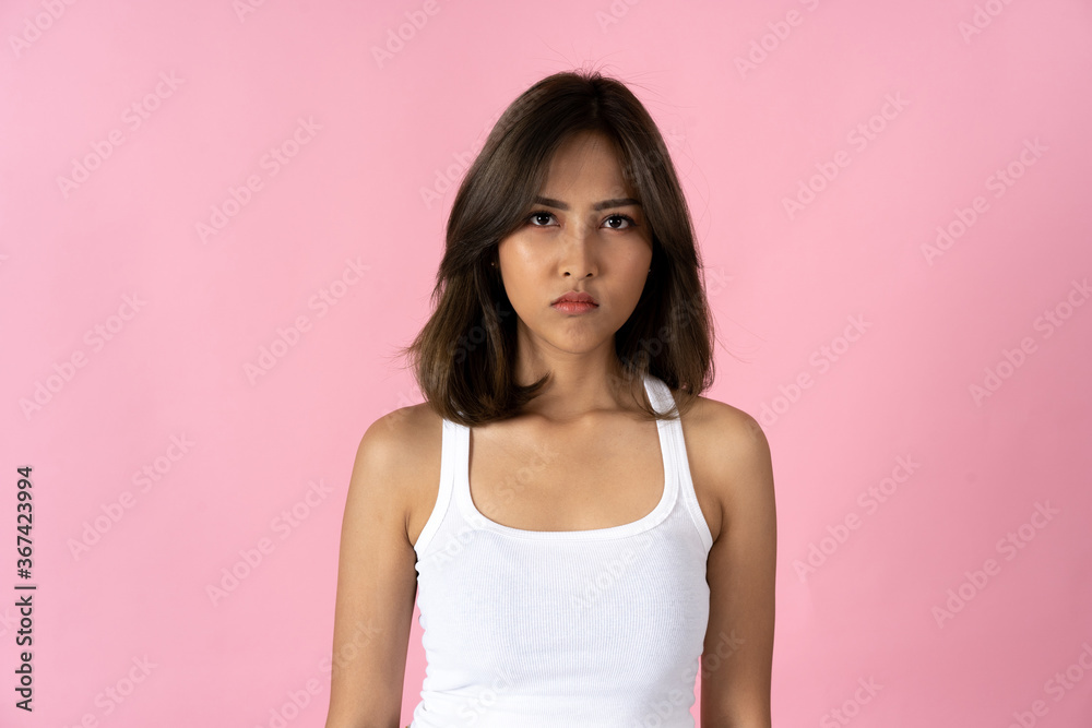 Serious young woman crossing arms and looking at camera against a plain pink background Serious young woman crossing arms and looking at camera against a plain pink background