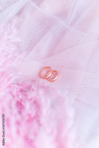 Wedding rings on pink tulle with pink feathers